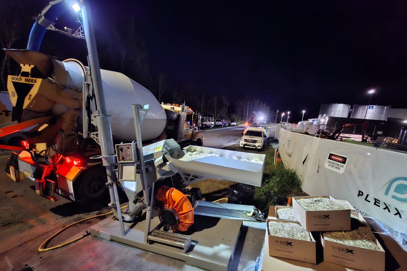 McClay fibre blower on site at night, blowing SteelX 5:25 from open boxes up into the drum of a concrete agitator truck